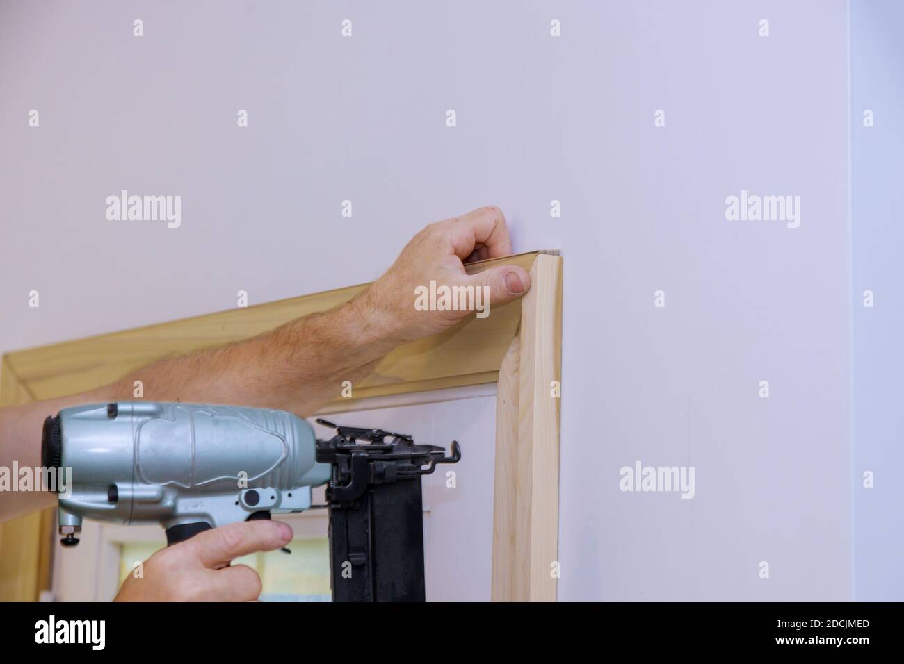 Carpenter installing nailing the framing trim to moldings on doors