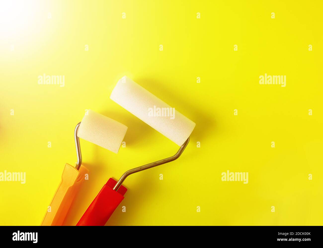 Home repair tools on bright yellow background. Two foam rollers for wall coloring close up. Stock Photo