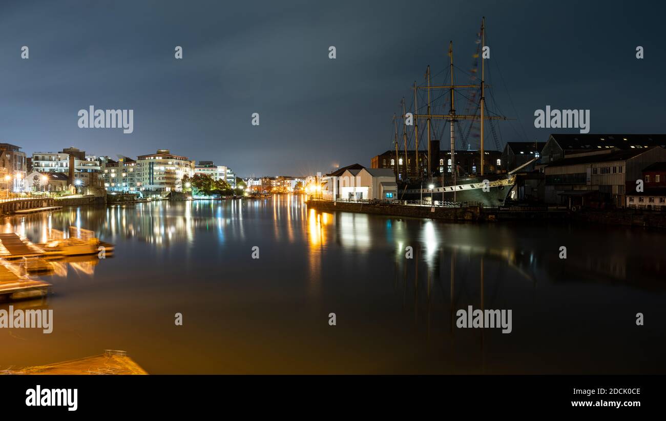 The SS Great Britain and modern apartment buildings are lit at night on