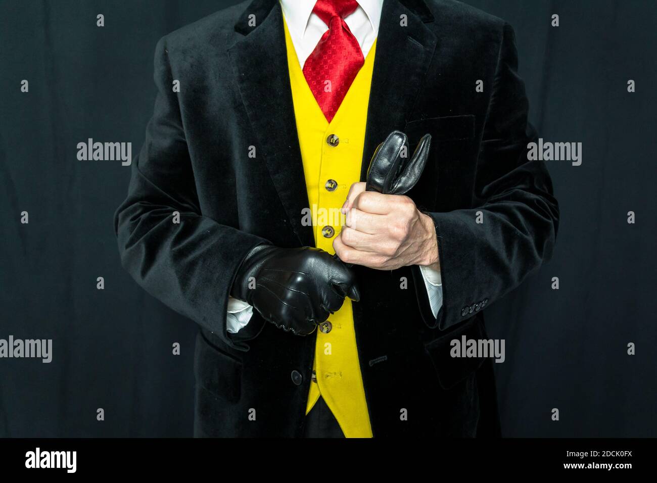 Portrait of Well Dressed Man in Bright Yellow Waistcoat and Red Tie Holding Leather Gloves. Stock Photo