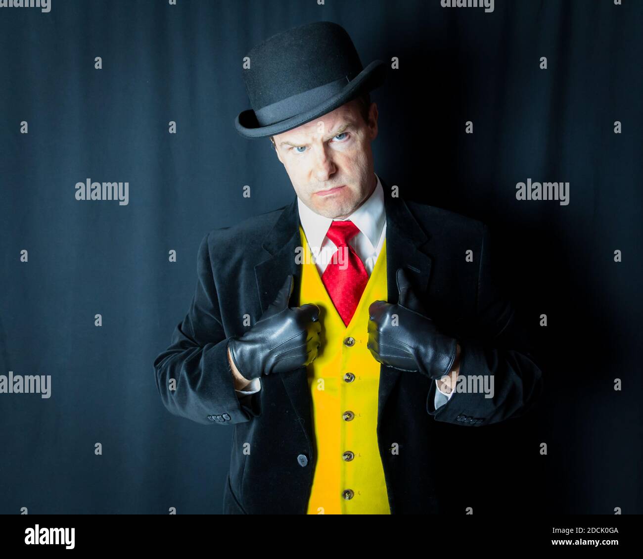 Portrait of Mean Looking Man in Bright Yellow Waistcoat and Leather Gloves. Concept of Comic Book Henchman. Dark Criminal Villain. Stock Photo