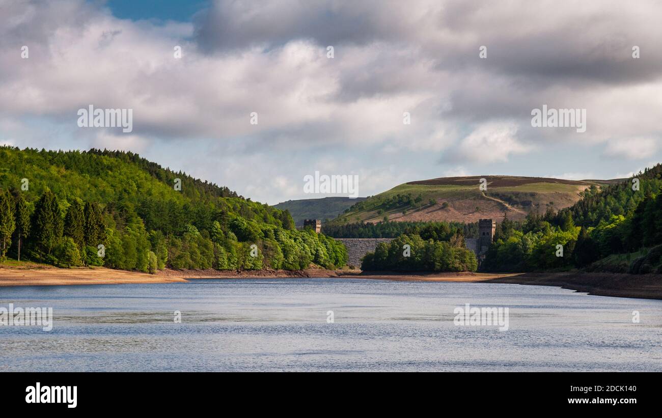 Low water reveals the shores of Derwent Reservoir, under Howden Dam and the wooded hills of the Derbyshire Peak District. Stock Photo