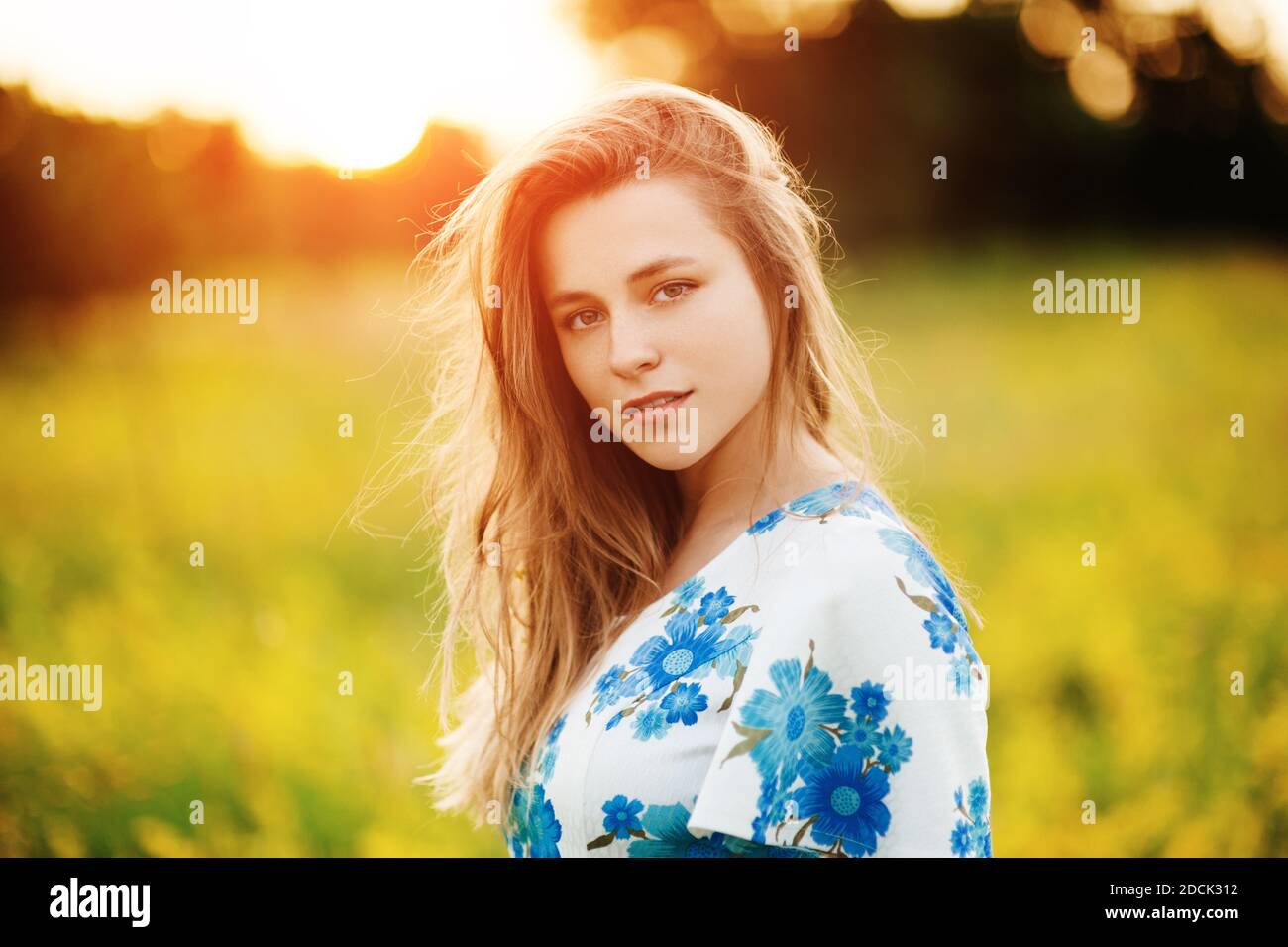 Beautiful tender cute girl on the flowers field Beautiful blonde woman in the flowers field in a multicolored dress on sunset light, Healthy Lifestyle Stock Photo