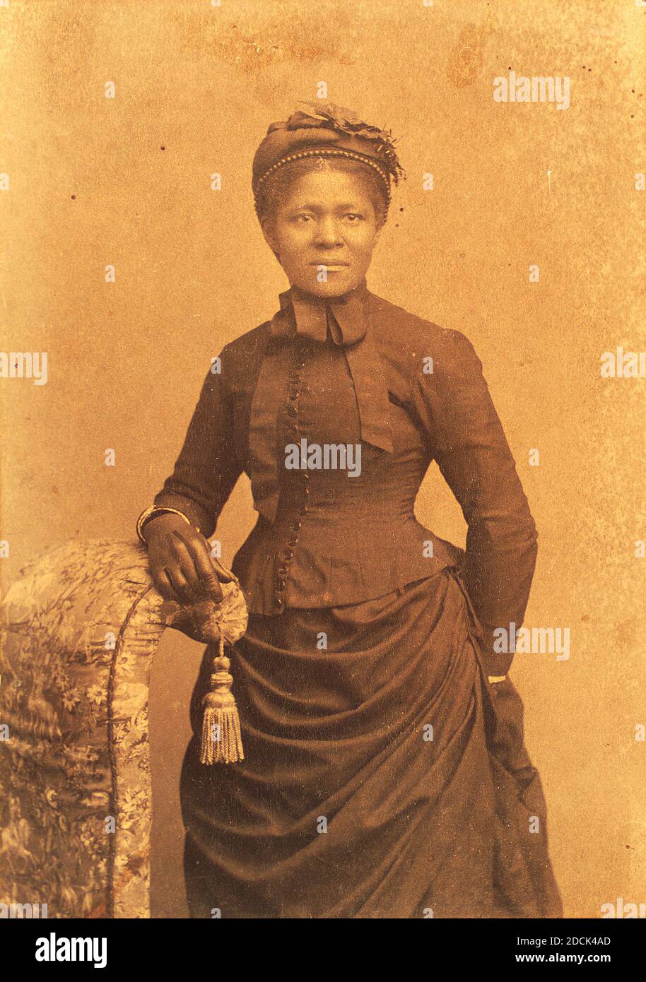 Studio portrait of woman wearing hat and gloves and dress with bustle