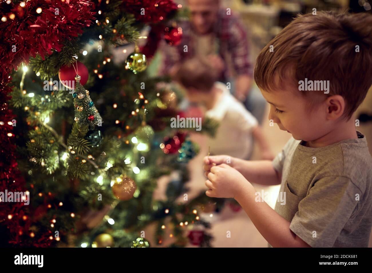 Happy family decorating a Christmas tree in a holiday atmosphere at home. Together, New Year, family, celebration Stock Photo