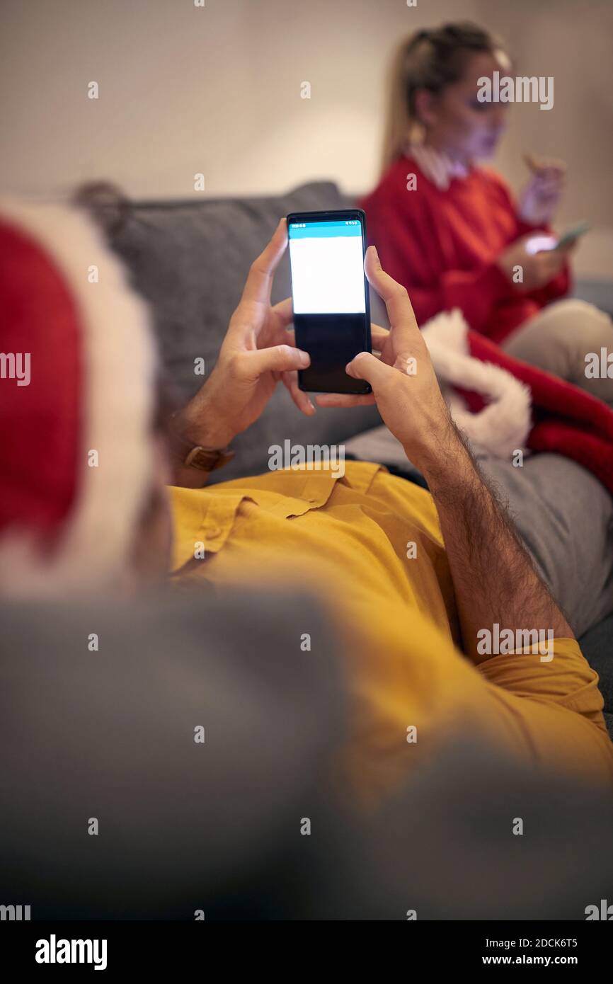 alone caucasian couple at home for christmas, typing on their cell phones. Corona, covid concept Stock Photo
