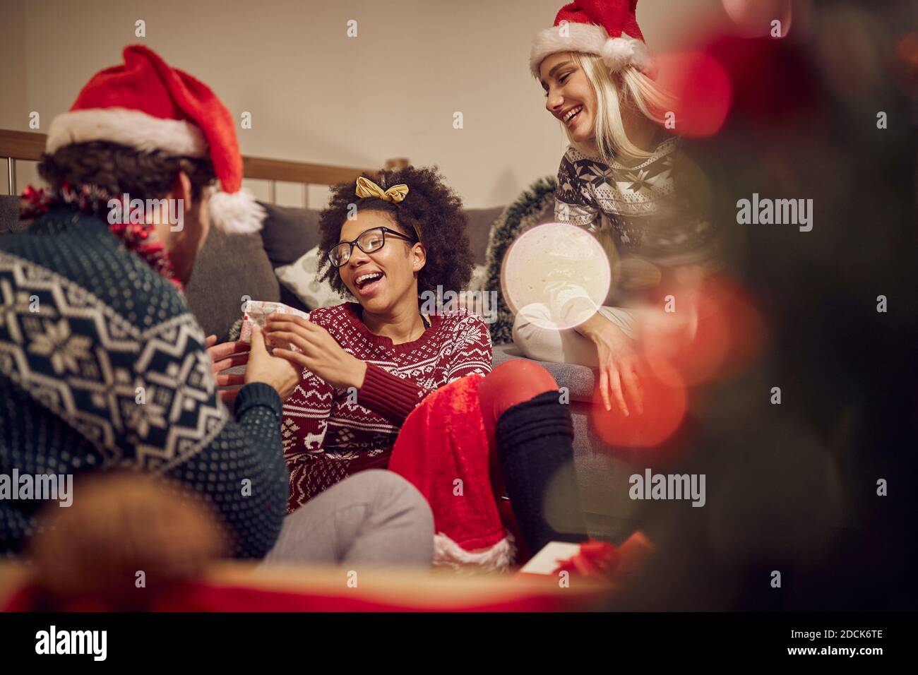 A young girl getting present from friend  in relaxed atmosphere at New Year's Eve home party. Xmas, New Year, friends, celebration Stock Photo