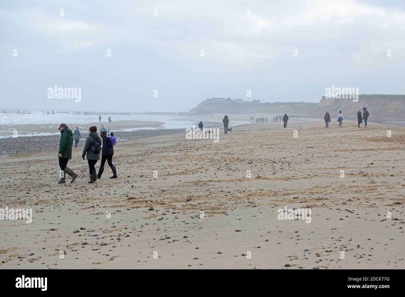 Winter weekend walkers, taking outdoor exercise on Happisburgh beach and coastline. Social distancing being respected. Norfolk. UK. Stock Photo