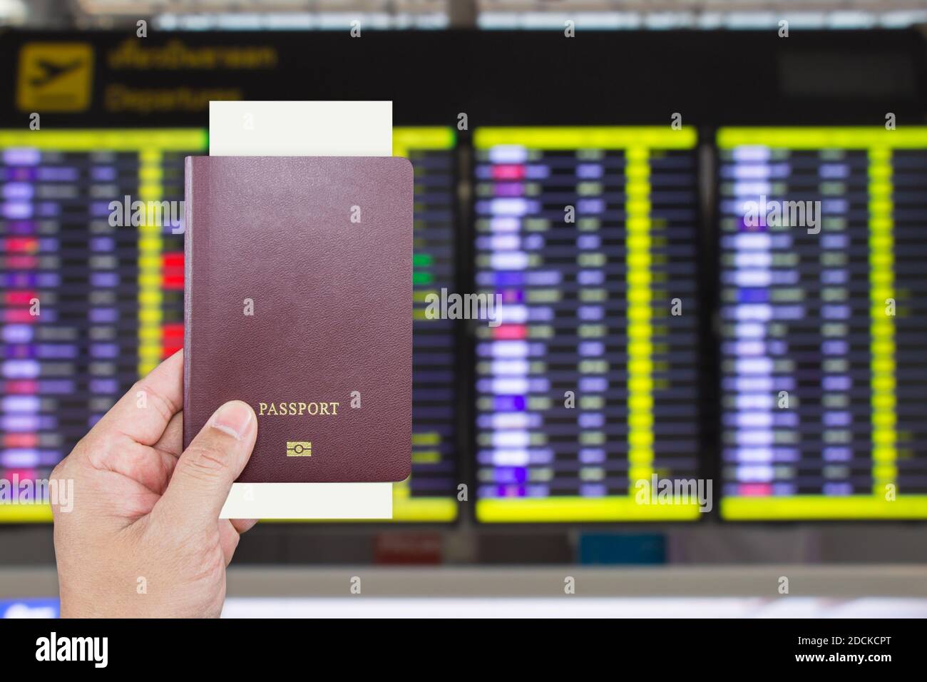 Passport with Boarding Pass in Male Hand with Blurry Flight  Departure Information Display Screen is Background Inside Suvarnabhumi Airport Samutpraka Stock Photo