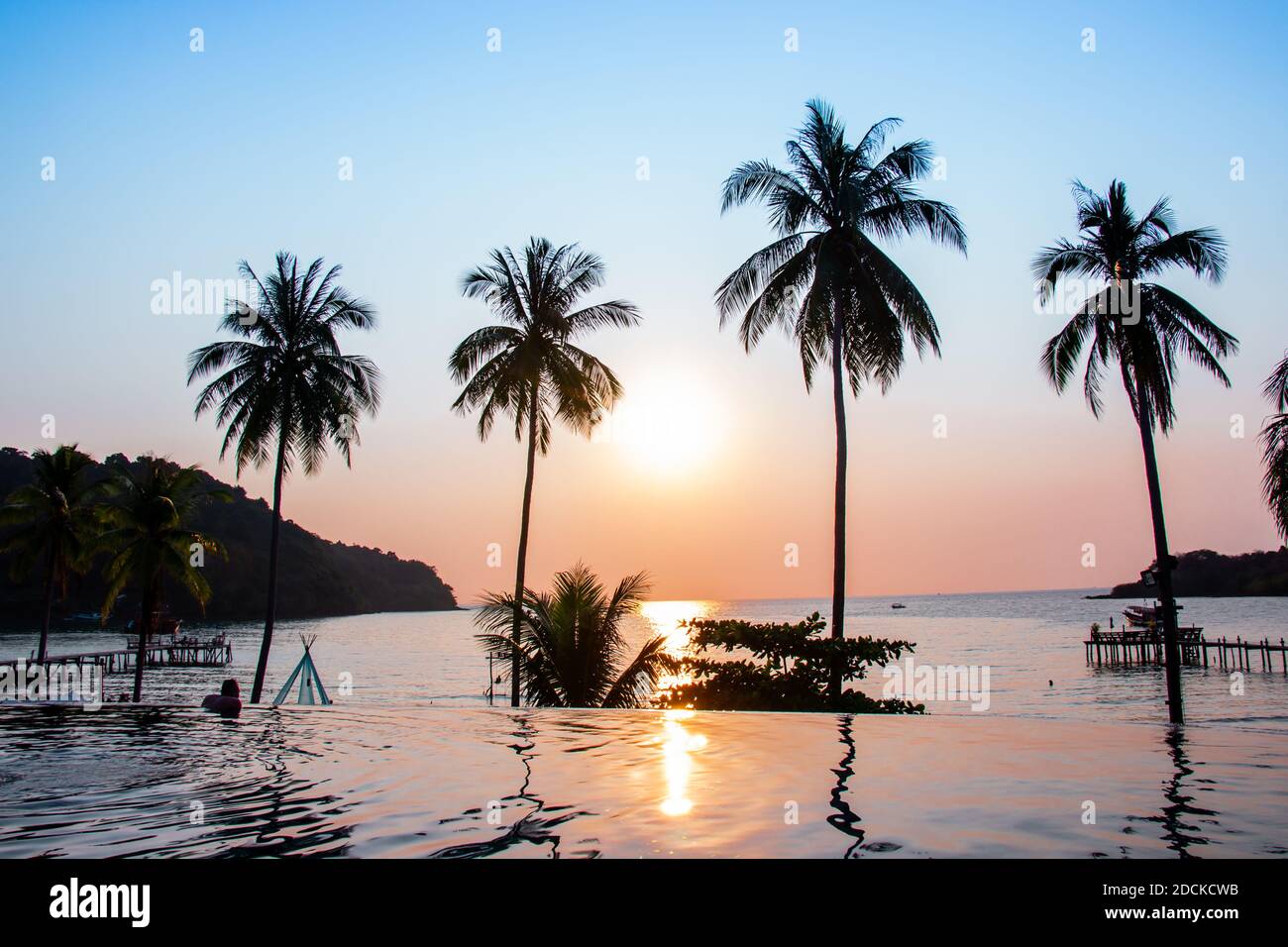 Sunset reflecting on the water surface foreground with coconut trees area ao bang bao at Koh Kood island is a district of Trat Province. Thailand. Stock Photo