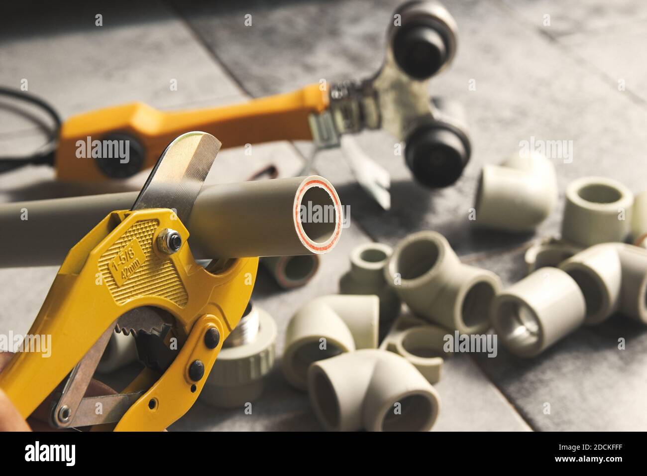 Closeup of hand plumber cuts polypropylene plastic pipes with scissors to solder a water pipe