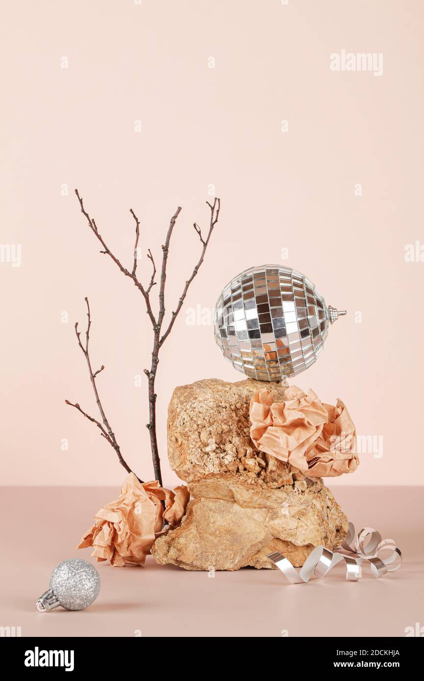 Christmas minimal style composition. disco ball , tree branch, crumpled paper on natural stone on beige background. merry christmas concept Stock Photo