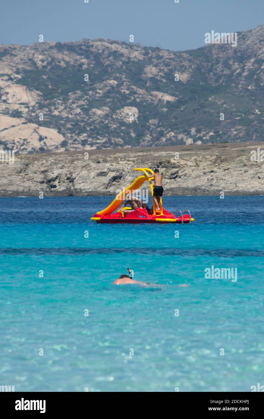 two people enjoy a pedal boat while a young man snorkels in the