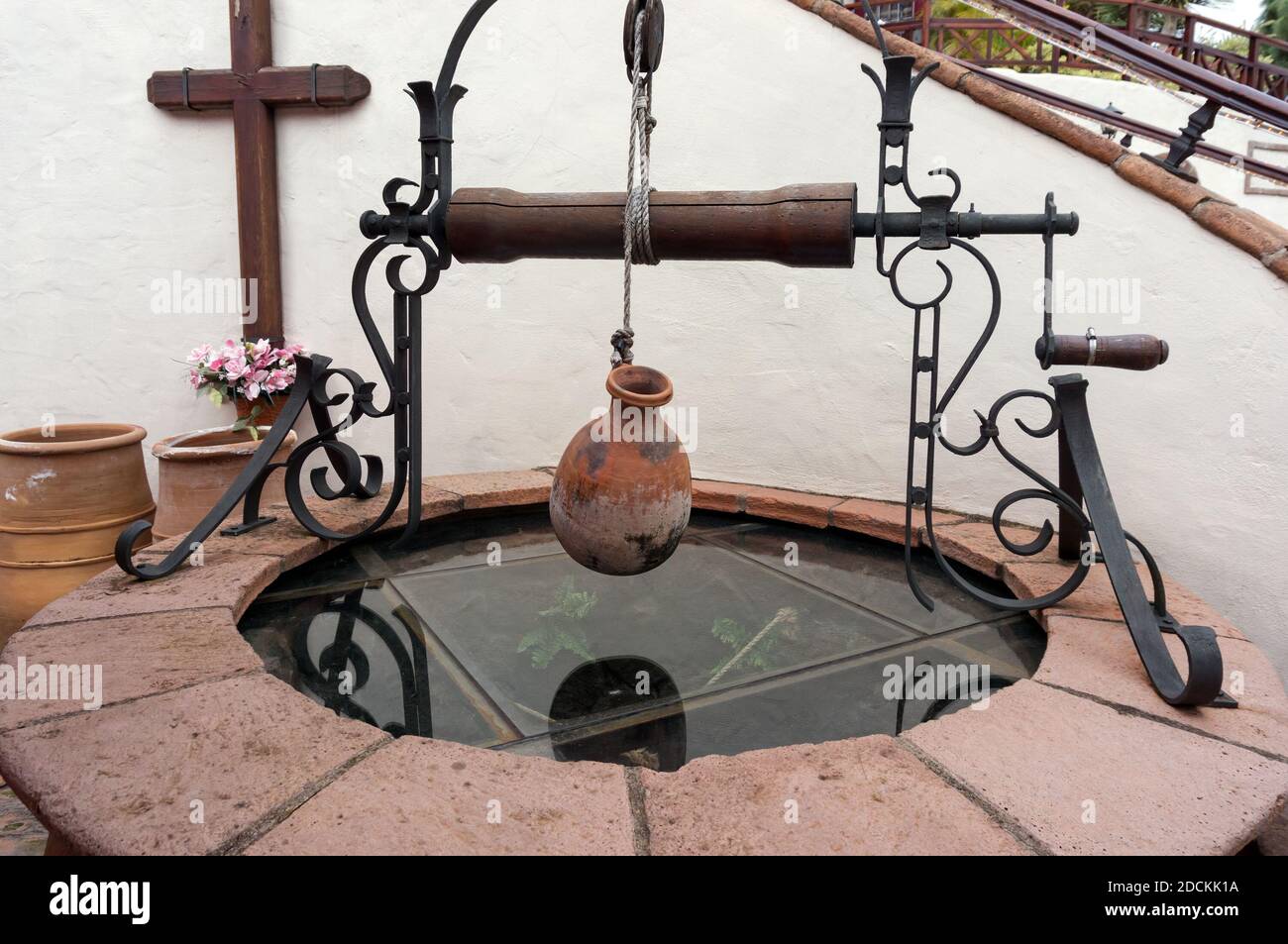 Ancient Spanish well with a hopper and a clay jug on a winch. Stock Photo