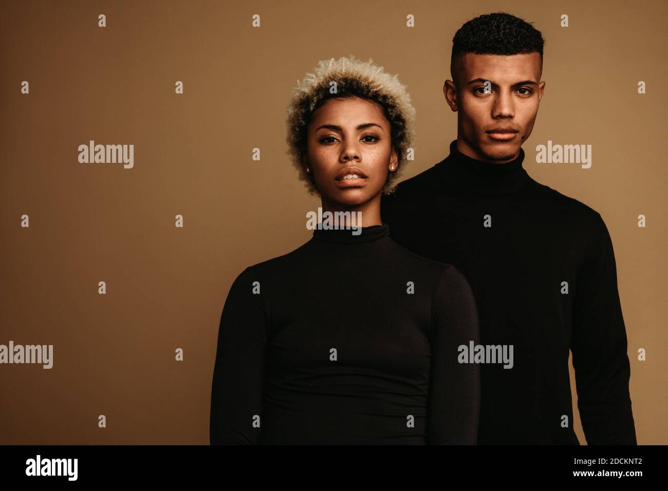 Couple on brown background in black clothes. Portrait of african american man and woman. Stock Photo