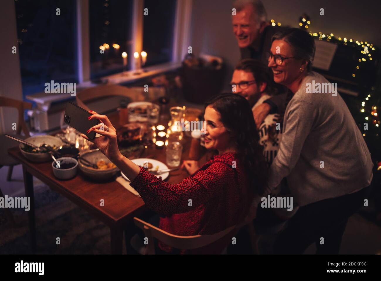 Family having a Thanksgiving dinner and having video chat with their loved one. Family having a video call during Christmas dinner. Stock Photo