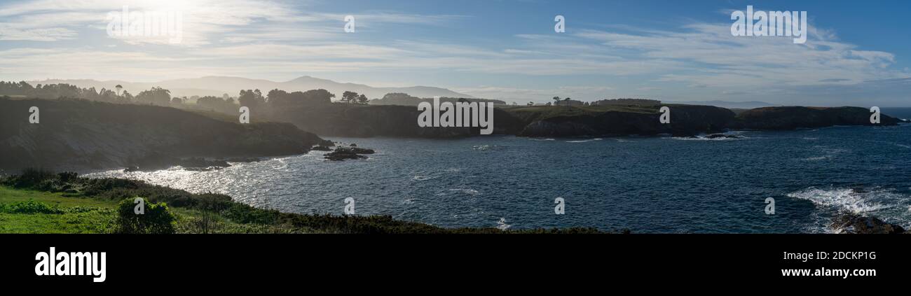 A panorama view of the misty and rocky tree-lined shore in Galicia Stock Photo