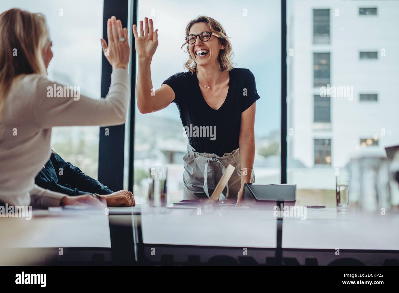 businesswoman giving high five to colleague in meeting. Happy business ...