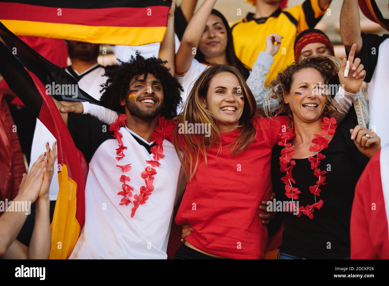 Excited group of a soccer fans from Germany cheering for their team. German football team supporters enjoying during a live match at stadium. Stock Photo