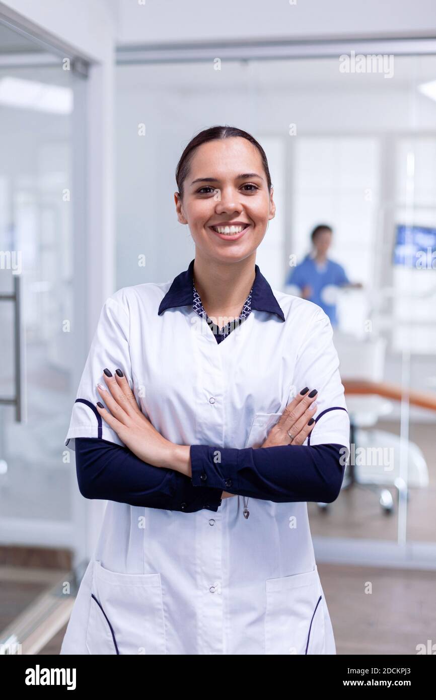 Portrait of teeth doctor in dental reception with arms crossed looking at camera wearing uniform