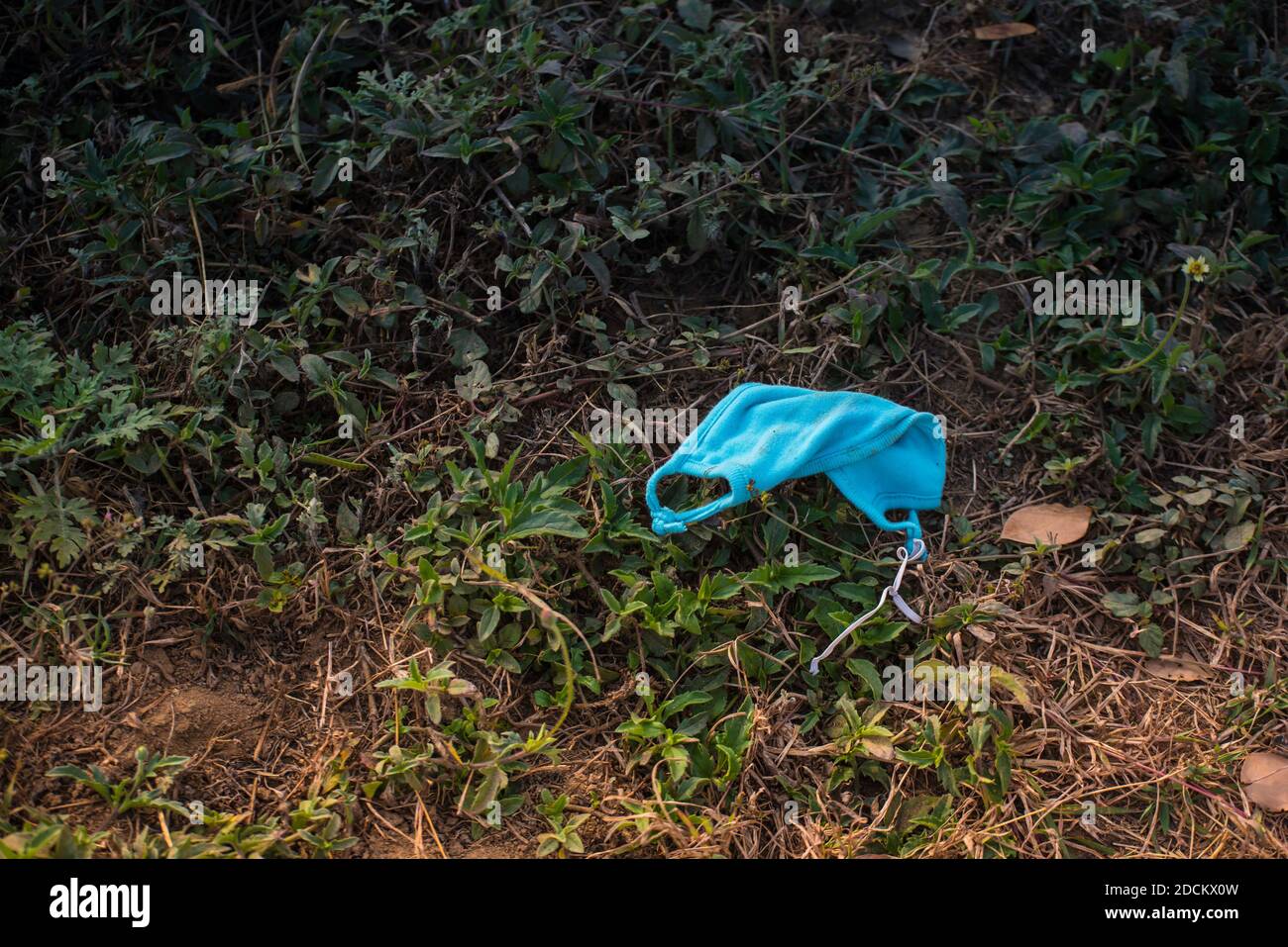 Used and very dirty mask lying on dirty soil. The debris from covid19. Stock Photo