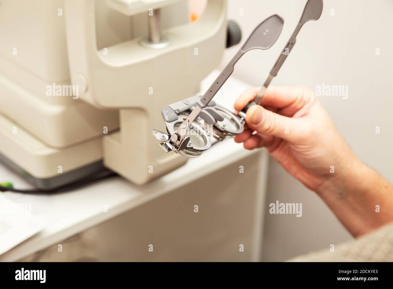 Man's hand holds an optometric trial frame for diopter adjustment. Ophthalmological clinic, vision examination. Stock Photo