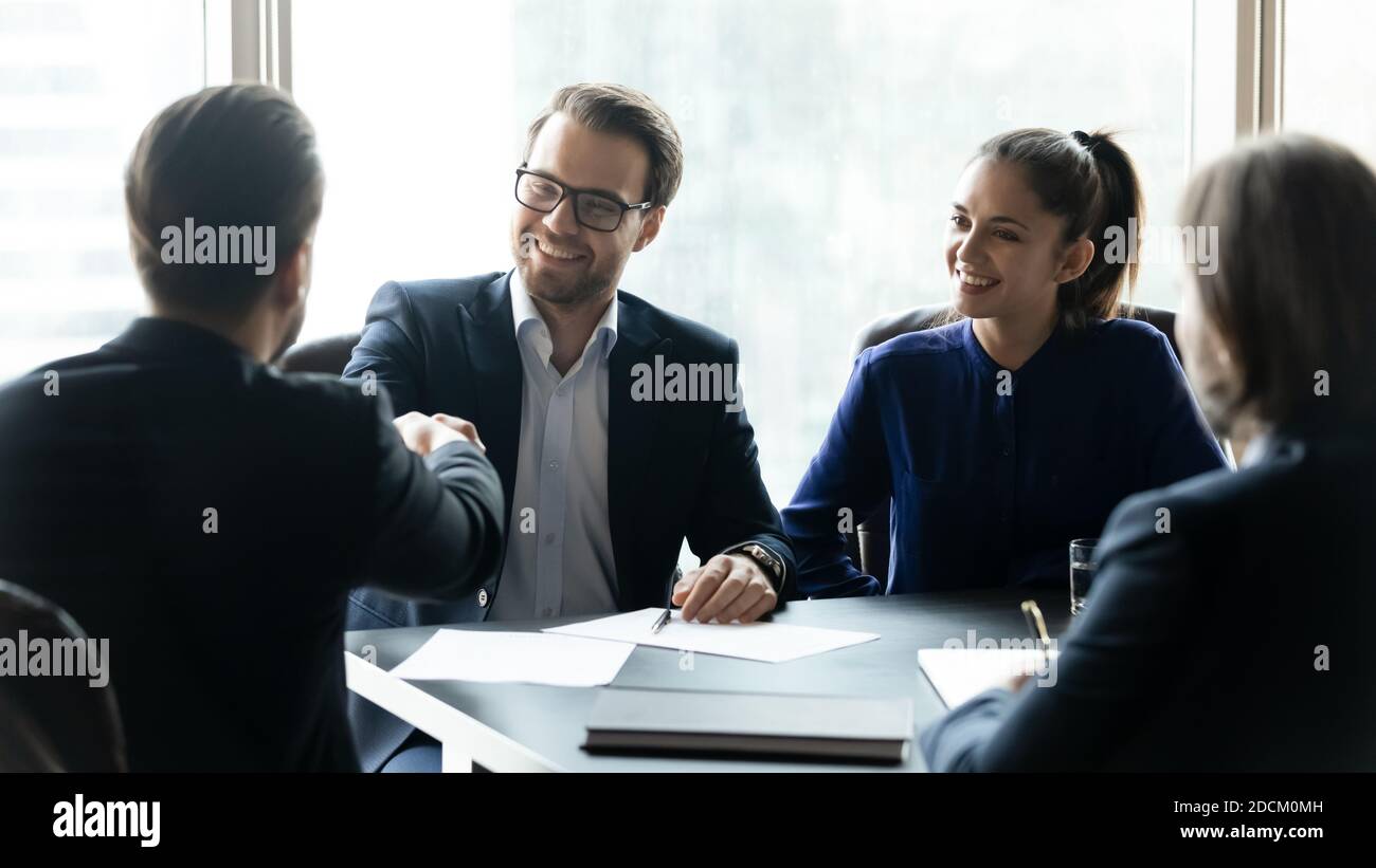 Smiling businesspeople shake hands at team briefing Stock Photo