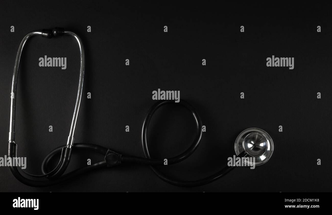 Medical instrument stethoscope phonendoscope on dark background. Device for listening to the lungs and heartbeat. Top view, copy space. Stock Photo