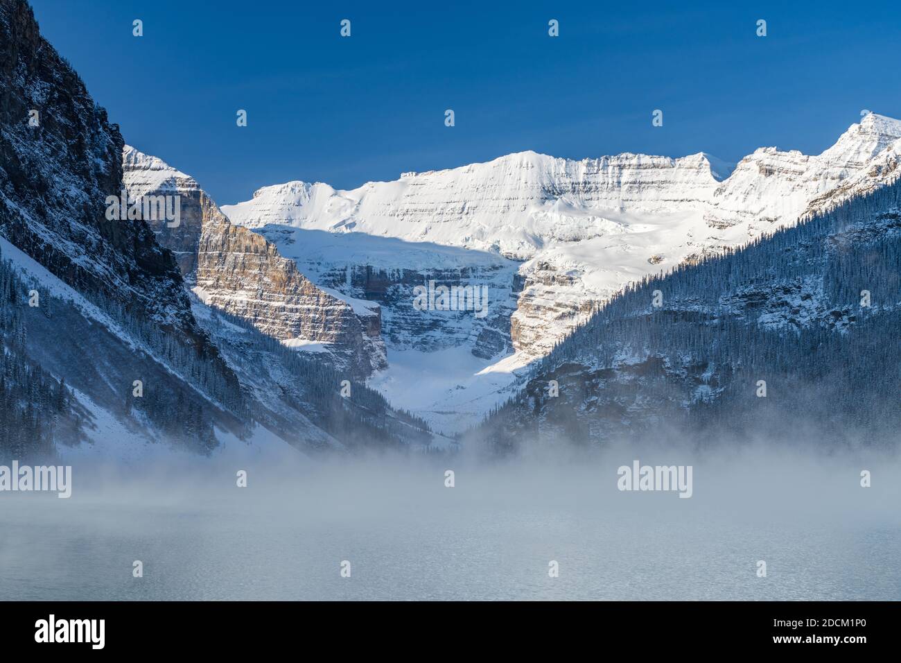 Lake Louise in early winter sunny day morning. Mist floating on ...