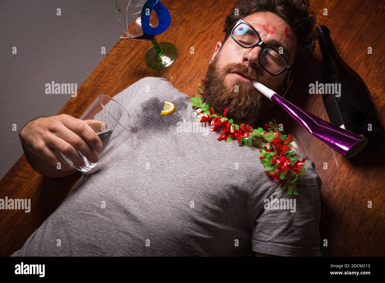 Boy with a hangover after a New Year's Eve party lying on the floor. Stock Photo