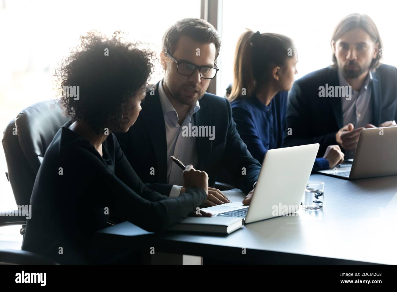 Multiracial colleagues work on laptops brainstorm at briefing Stock ...