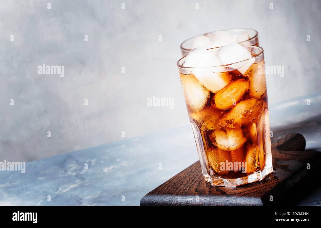 Alcoholic cocktail of rum-cola with ice, gray background, selective focus Stock Photo