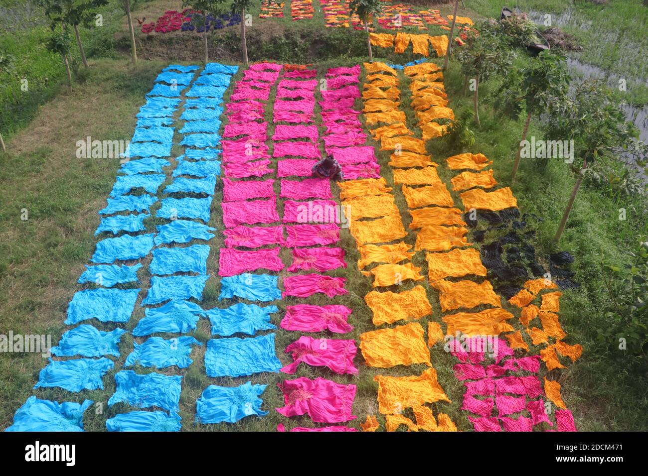 Bangladeshi workers collect fabric after dry them under the sun at a dyeing factory in Narayanganj, Bangladesh. Nazmul Islam/Alamy Stock Photo Stock Photo