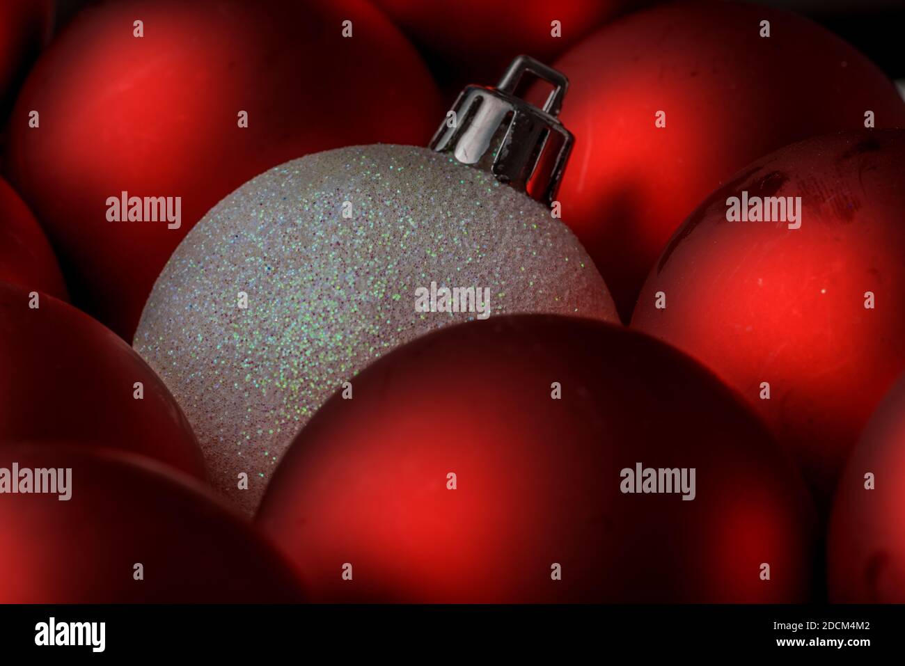 a glittered white Christmas Decoration Balls pop out from a group of red  balls. originality. concept. horizontal close up Stock Photo - Alamy