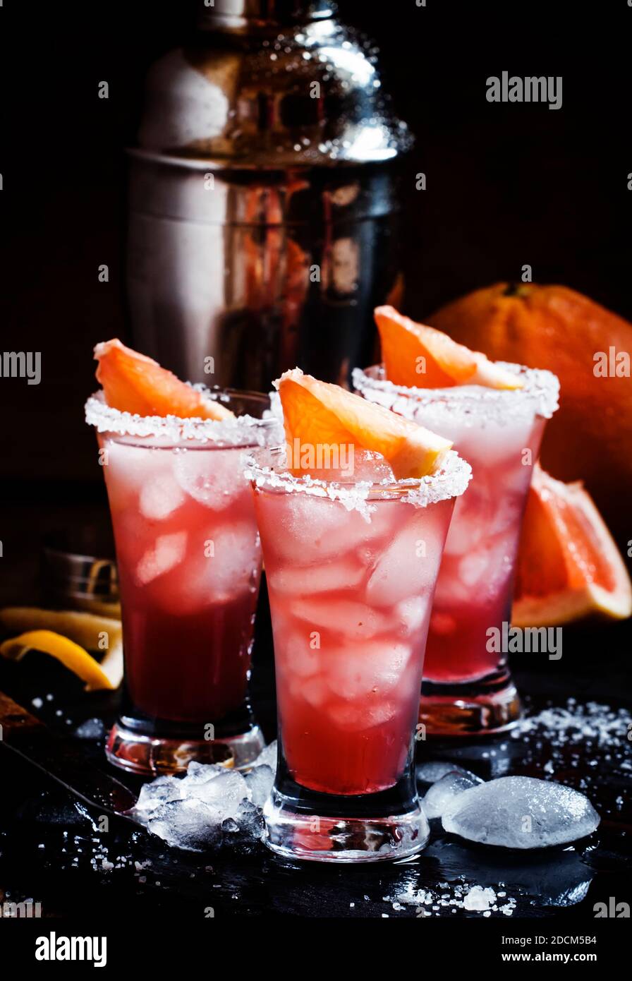 Cocktail salty dog with grapefruit juice, vodka, salt and ice, black background, selective focus