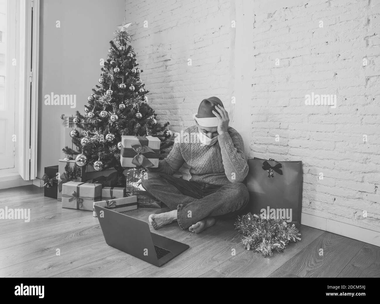 Sad man with face mask video calling family and friends feeling depressed home alone in lockdown at christmas. COVID-19 virtual holiday celebrations, Stock Photo