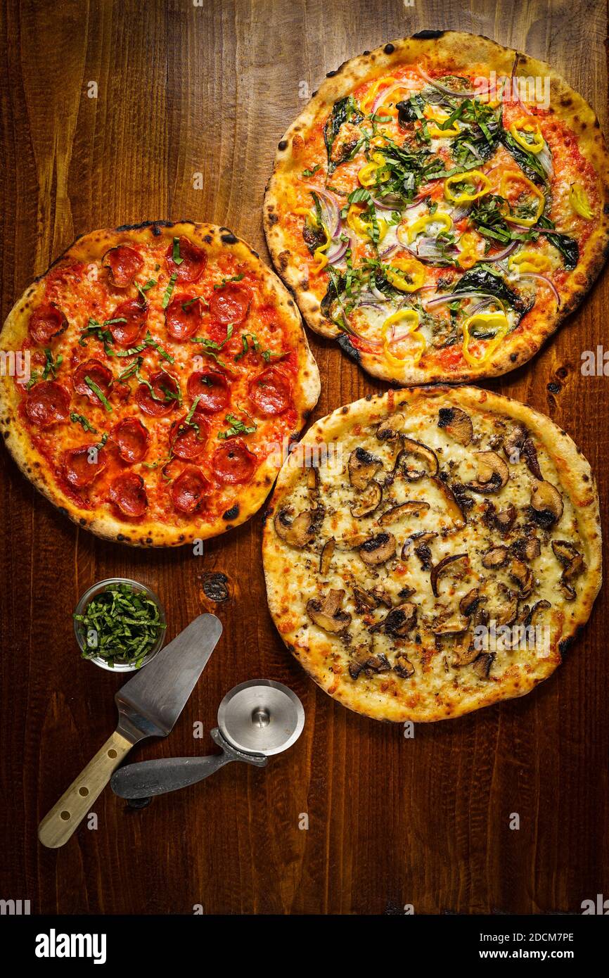 Three pizzas on a wooden board Stock Photo