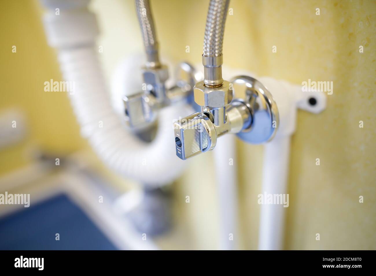 Shallow depth of field (selective focus) image with a metal water tap under a sink. Stock Photo