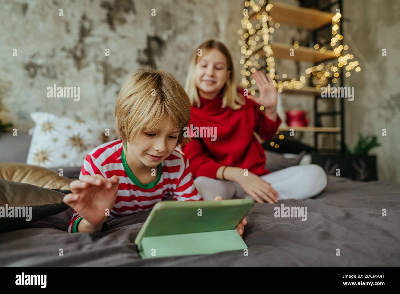 Boy and girl using tablets for video call in Christmas time. Selective focus on the boy. Stock Photo