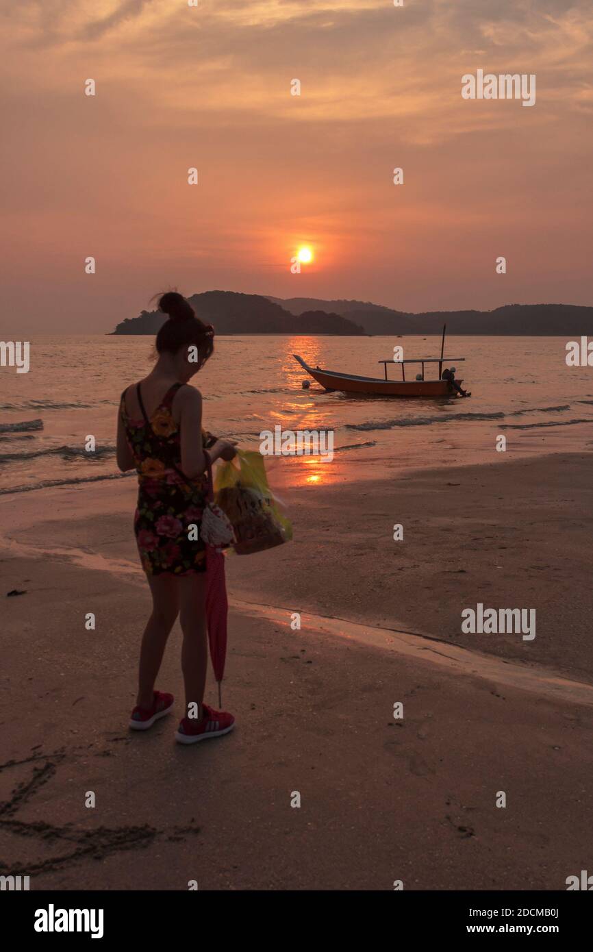 A woman checking her plastic bag at the beach. Stock Photo