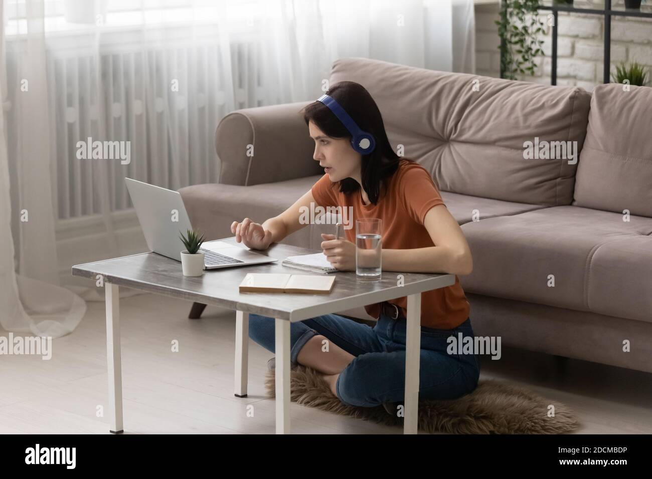 Focused young woman in headphones watching educational lecture on ...