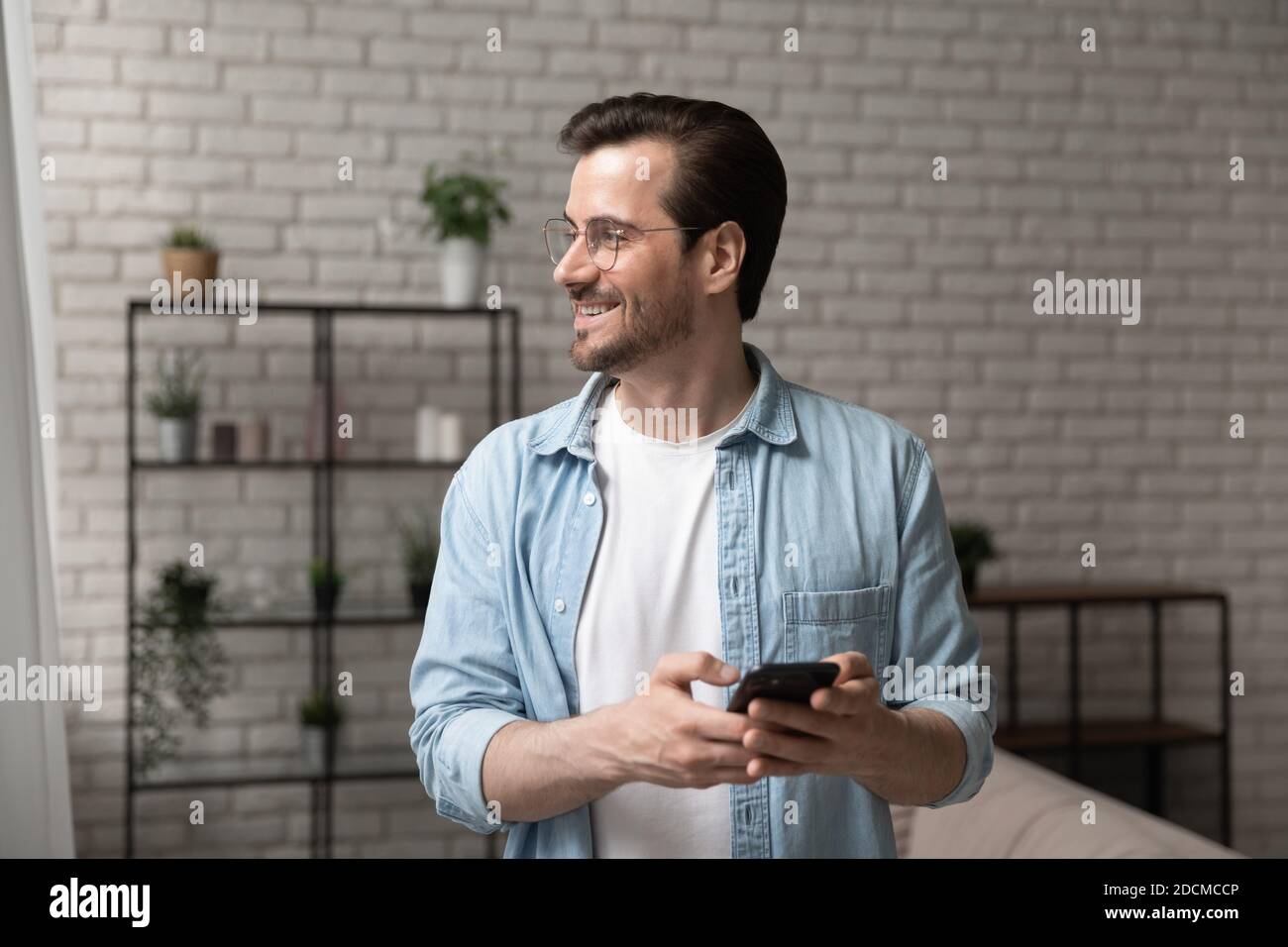 Dreamy young 30s man in eyeglasses looking in distance. Stock Photo