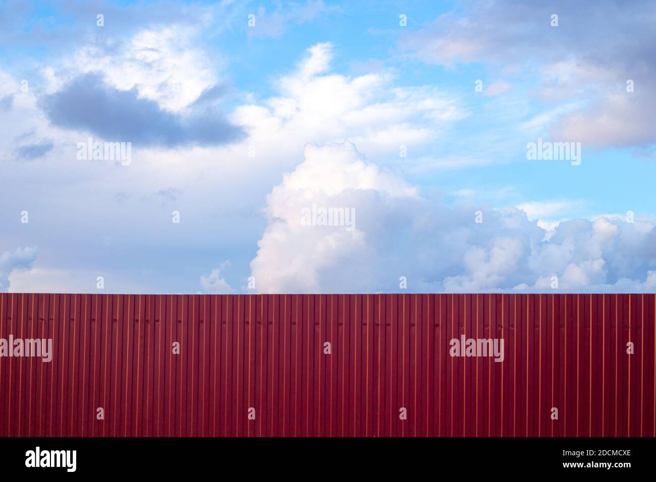 blue sky with clouds behind a burgundy fence, copy space. Freedom concept, border closure. Stock Photo