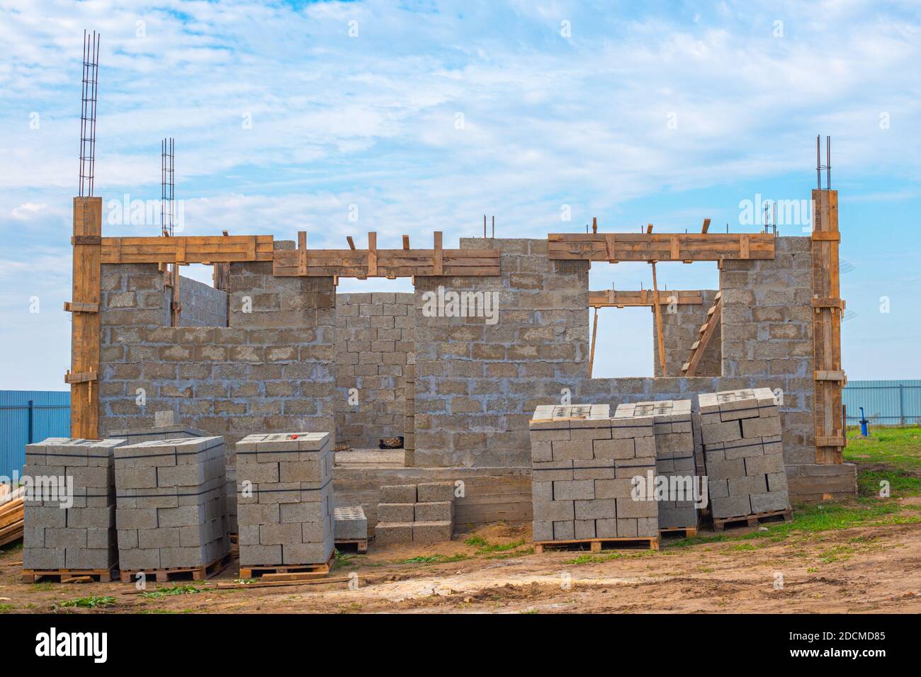Construction stages. Cinder block house with protruding fittings, ground floor. Building material stacked on pallets. Stock Photo