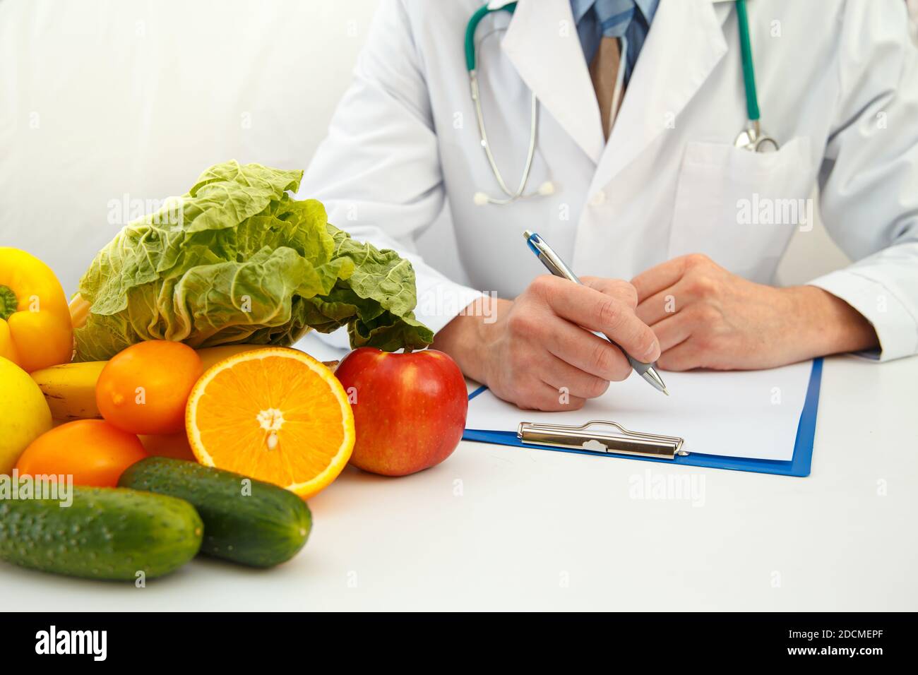 Nutritionist doctor writing diet plan on table. Right nutrition and slimming concept Stock Photo