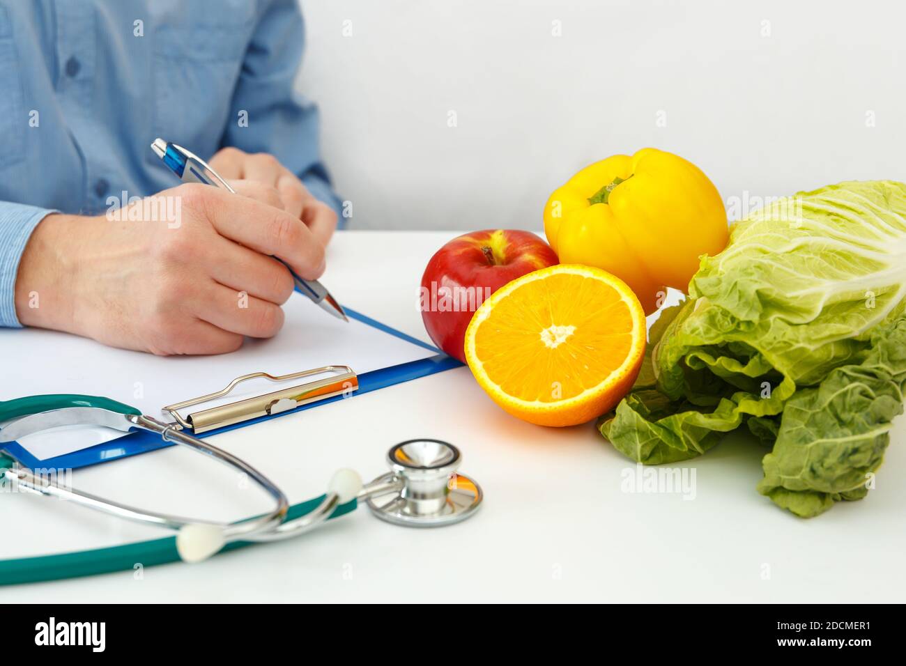 Nutritionist doctor writing diet plan on table. Right nutrition and slimming concept Stock Photo