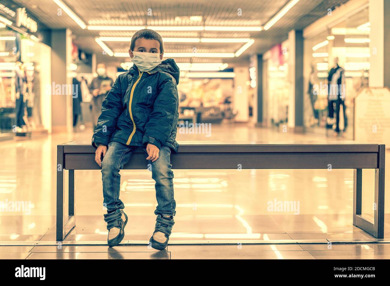 Toddler child, boy, wearing protective medical mask in shopping center during coronavirus Covid 19 pandemic. The child wears a protective mask in the Stock Photo