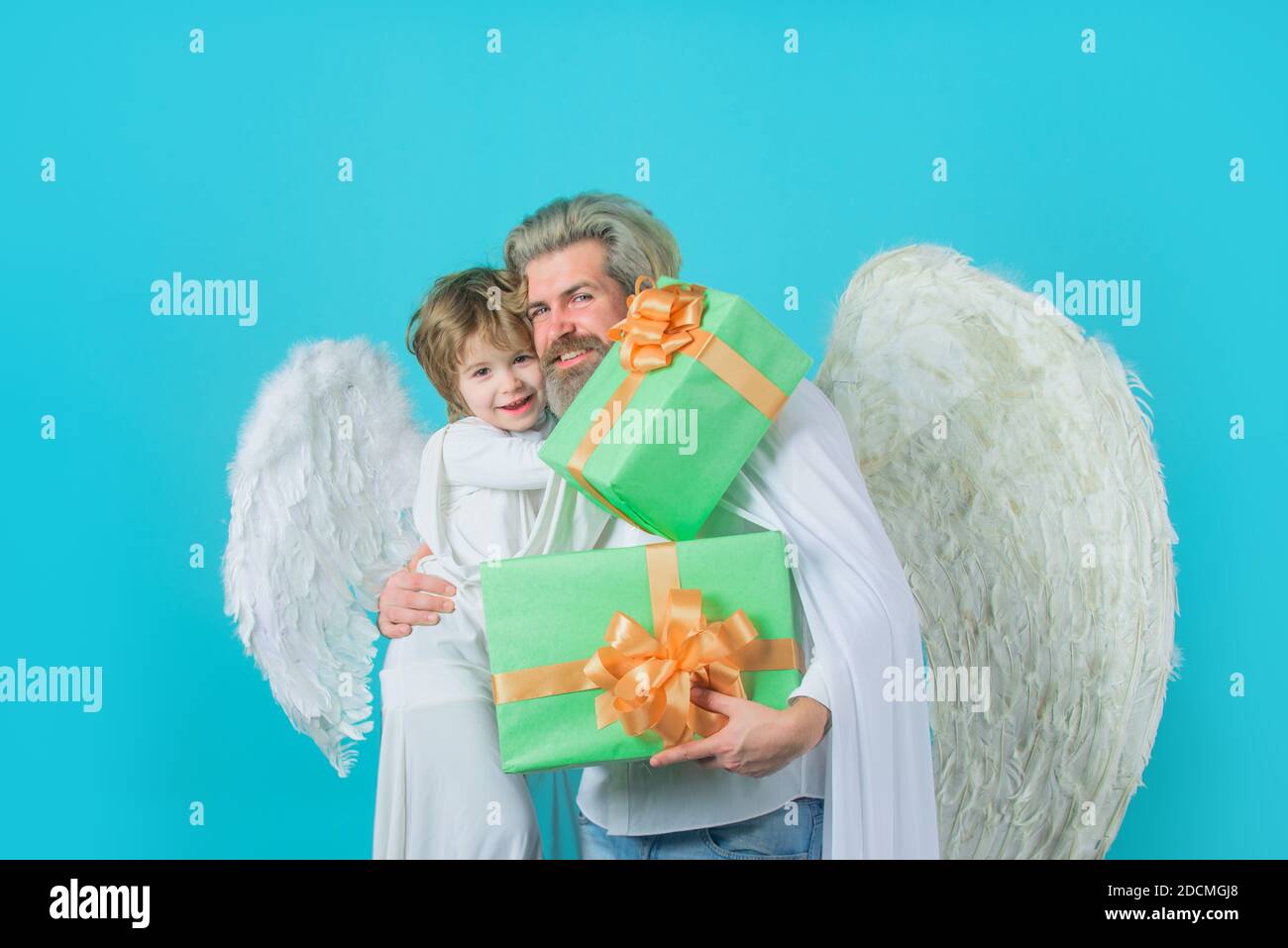 Valentines angels. Valentines day. Little cupid boy gives father gift. Gift box. Family in angel costumes. Cute angel. Father and son Angels Stock Photo