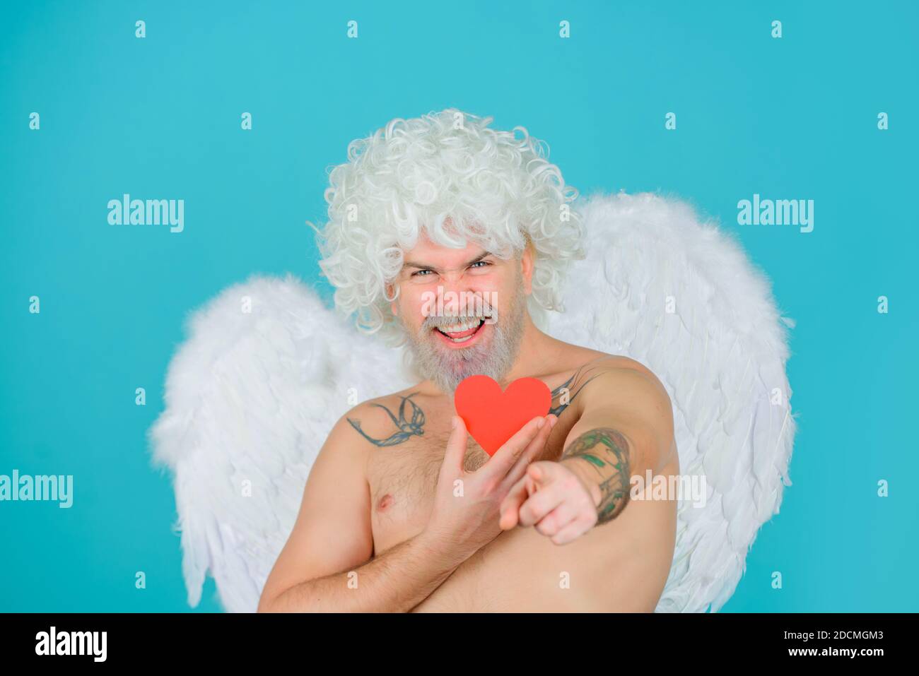 Valentines day cupid. Bearded angel with paper heart. Cupid in valentine day. Bearded cupid. Valentine day. Valentines Day. Angel with heart Stock Photo