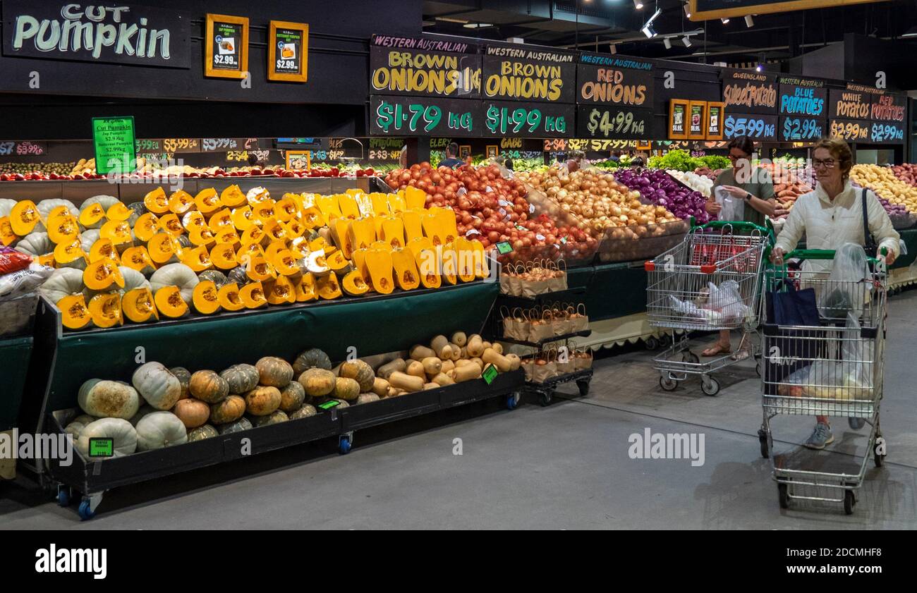 Two women with shopping trolleys carts shopping for vegetables at